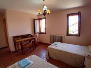 a bedroom with two beds and a table and a desk at Casa Flor de Rello in Rello