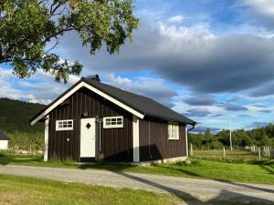a brown barn with a white door on a road at Tørresvangen in Tynset