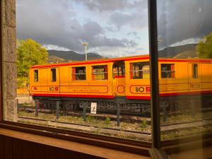 a yellow train sitting on the tracks next to a window at L'auberge de la Ludogare in Saillagouse