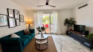 a living room with a green couch and a tv at Carihuela Playa Los Nidos 1 in Torremolinos