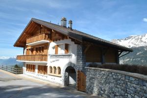 a house with a stone wall and a mountain at Les Petits Mélèzes in Crans-Montana