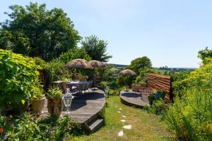 a wooden deck with chairs and umbrellas in a garden at Droom op de Vijlenberg in Vijlen