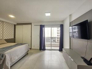 a bedroom with a bed and a flat screen tv at Studio Mobiliado no Independência 915 in Juiz de Fora