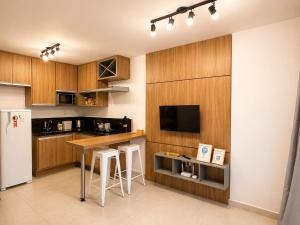 a kitchen with wooden cabinets and a counter with stools at Studio Mobiliado no Independência 915 in Juiz de Fora
