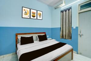 a bedroom with a bed with blue walls and a window at Hotel O Urban Rooms in Neemrana