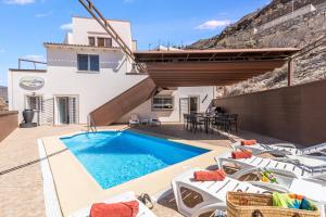 a villa with a swimming pool and a house at Moser Living Premium Apartments - Puerto Rico in Mogán