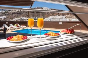 a table with plates of food and glasses of orange juice at Moser Living Premium Apartments - Puerto Rico in Mogán