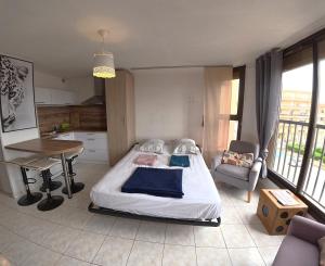 a bedroom with a bed and a table and a kitchen at Charmant studio Toi et Moi à 30 m de la plage et de Valras centre avec linge de lit et ménage inclus in Valras-Plage