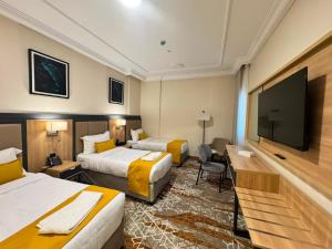 a hotel room with two beds and a flat screen tv at فندق بارك برايم - Park Prime Hotel in Mecca