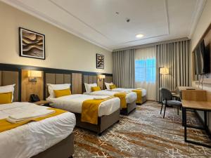 a hotel room with three beds and a desk at فندق بارك برايم - Park Prime Hotel in Mecca