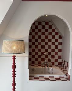 a bathroom with a bath tub with a checkered wall at Florès Boutique Hotel in Zwolle