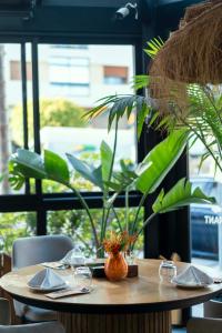 a wooden table with plates and glasses and plants at Flamant Rose Appart Hotel in Tangier