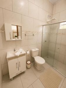 a white bathroom with a toilet and a shower at Loft Farol in Pântano Grande