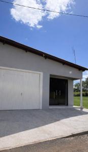a white building with a garage at Loft Farol in Pântano Grande