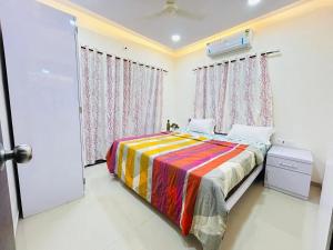a bedroom with a bed with a colorful blanket at Orchid Villa - The Dream Stays ll Big Pvt Pool ll 3Ac room ll Wi-Fi ll Tv in Lonavala