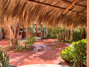 a patio with a large straw pavilion with trees and plants at M a r e a V i v a - Z i p o l i t e in Zipolite