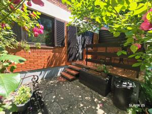 a bench in front of a house with flowers at Kuća za odmor SLAVIK in Daruvar +4 photos