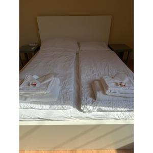 a bed with white blankets and towels on it at TIÉD Apartman in Kiskunmajsa +5 photos