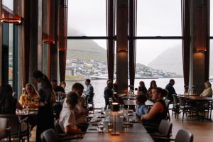 Eine Gruppe von Menschen sitzt an Tischen in einem Restaurant in der Unterkunft KG Hotel in Klaksvík