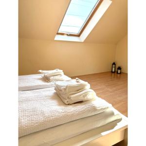 a bedroom with a bed with white sheets and a skylight at TIÉD Apartman in Kiskunmajsa