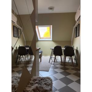 a dining room with chairs and a table and a window at TIÉD Apartman in Kiskunmajsa