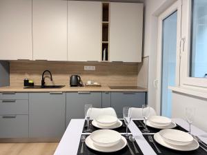 a kitchen with a dining table with white cabinets at Apartman H4 in Žilina