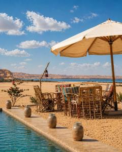 a table and chairs and an umbrella on a beach at Soléi Desert Retreat in Siwa