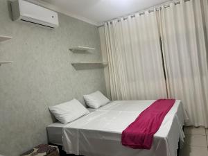 a bedroom with a white bed with a pink blanket on it at Chácara HZ in Sao Jose do Rio Preto