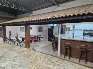 an outdoor kitchen with a bar with chairs and tables at Chácara HZ in Sao Jose do Rio Preto