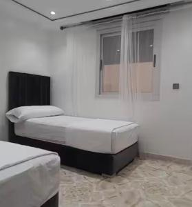 two beds in a white room with a window at Apartamento dina 13 in Fnidek