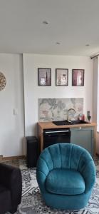 a living room with a blue chair and a sink at La Pomponnette in Sedan