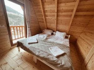 a bed in a wooden room with a large window at Bujtina n'kullë in Boge