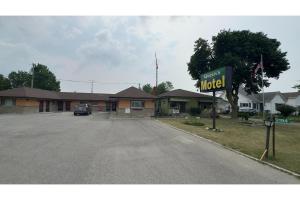 a motel sign in front of a parking lot at Queen's Motel Blenheim Near Lake Erie ON in Blenheim