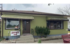 a small green house with a for sale sign in front at Queen's Motel Blenheim Near Lake Erie ON in Blenheim
