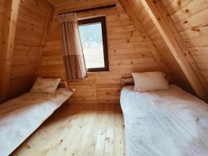 two beds in a log cabin with a window at Bujtina n'kullë in Boge