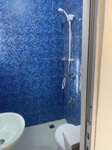 a blue tiled shower with a toilet and a sink at pavillon « lilas » à dagué-togo in Dagé