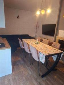 a dining room table with chairs and a table and a television at Apartament dwupoziomowy z 2 sypialniami in Ujazdowo