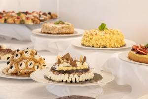a table filled with different types of cakes on plates at Hotel Globus Pool & Beach in Milano Marittima +141 photos