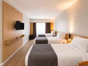 a hotel room with two beds and a flat screen tv at Hotel & Residence Sol Alphaville Flat in Barueri