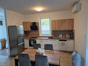 a kitchen with a table and a stainless steel refrigerator at Riverside house Duna in Rajka +9 photos