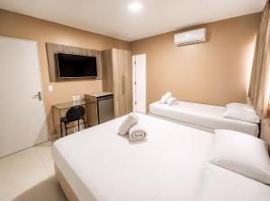 a hotel room with two beds and a television at Hotel Itaparica in Caruaru