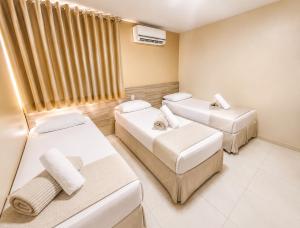 a room with three beds and a tv at Hotel Itaparica in Caruaru +1 photo