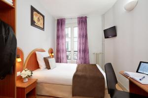 パリにあるオテル ヴィアトールのベッドとデスクが備わるホテルルームです。