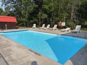 a blue swimming pool with lounge chairs and a red building at The Perch on Black Lake in Hammond