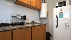 a kitchen with wooden cabinets and a white refrigerator at Apart Escobar in Belén de Escobar
