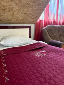 una camera da letto con un letto con una coperta rossa e una sedia di Ноу a Goris