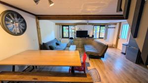 a living room with a table and a clock on the wall at La carrouere in Gujan-Mestras +3 photos