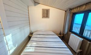 a small bed in a room with two windows at La carrouere in Gujan-Mestras