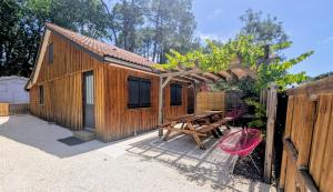 a wooden cabin with a picnic table and a fence at La carrouere in Gujan-Mestras