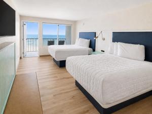 a hotel room with two beds and a balcony at Palm & Tide Beachfront Hotel in Panama City Beach